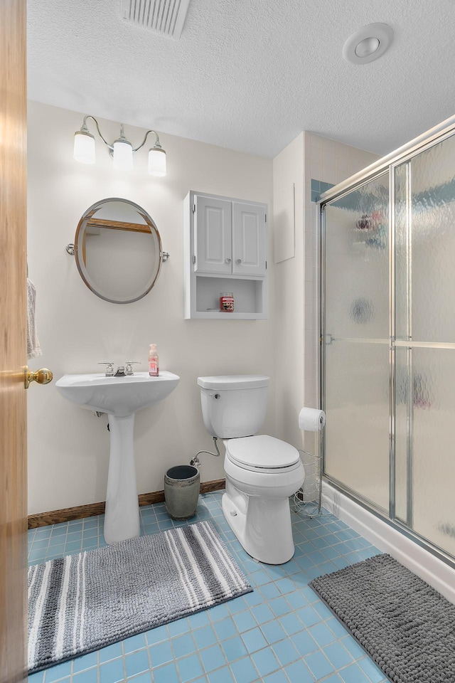 bathroom with visible vents, a textured ceiling, a stall shower, and toilet