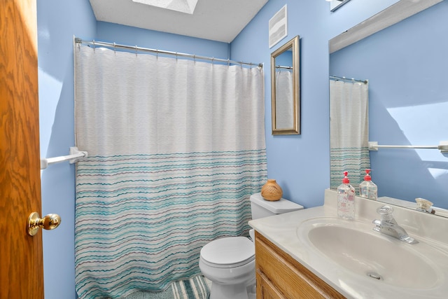 bathroom with a skylight, vanity, and toilet