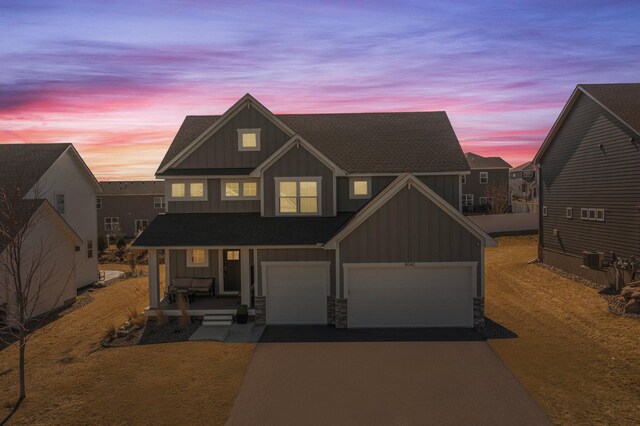 view of front of home with board and batten siding, aphalt driveway, a porch, and a garage