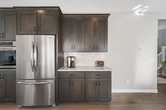 kitchen featuring light countertops, stainless steel appliances, tasteful backsplash, and dark brown cabinets