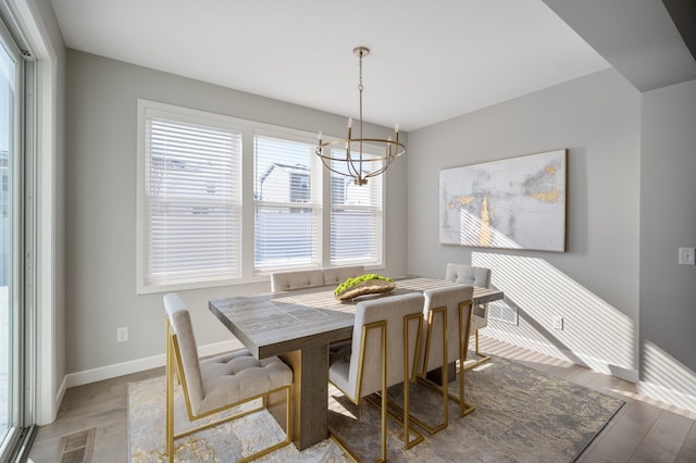 dining room with visible vents, baseboards, light wood finished floors, and a chandelier