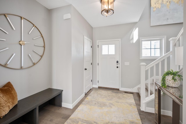 entrance foyer with stairs, baseboards, visible vents, and wood finished floors