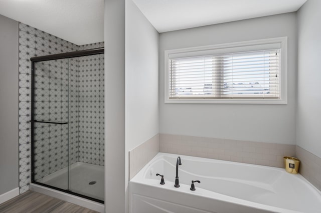 bathroom featuring wood finished floors, a garden tub, and a stall shower