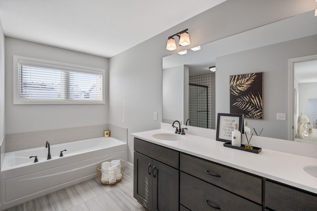 full bath featuring a garden tub, a sink, a stall shower, and double vanity
