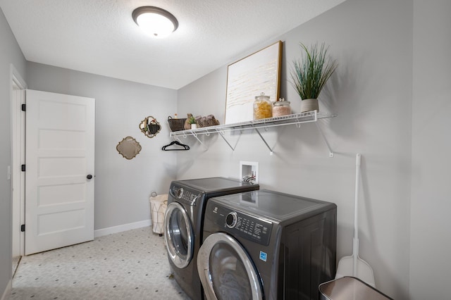 laundry room featuring laundry area, baseboards, light floors, a textured ceiling, and separate washer and dryer