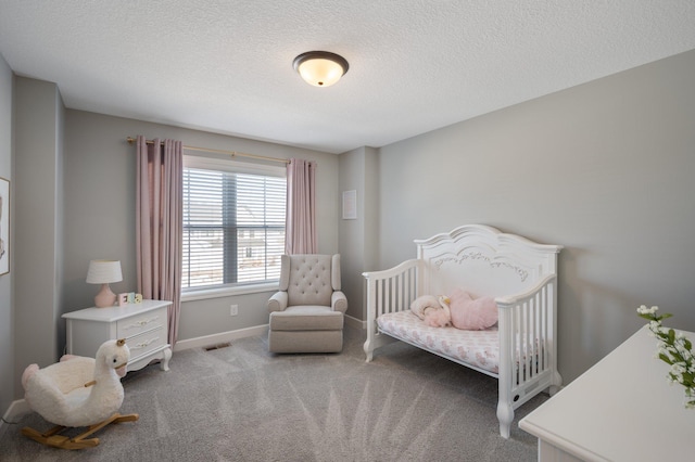 carpeted bedroom featuring baseboards, a nursery area, a textured ceiling, and visible vents