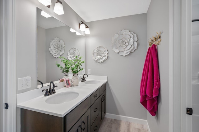 bathroom with double vanity, a sink, baseboards, and wood finished floors