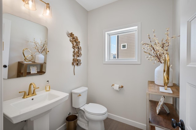 bathroom with a sink, baseboards, toilet, and wood finished floors