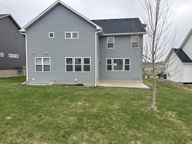 back of property with a yard, a patio, and roof with shingles