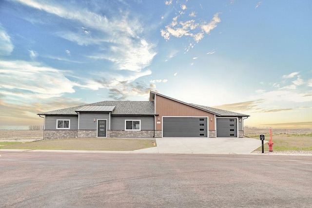 view of front facade featuring a garage, stone siding, and concrete driveway