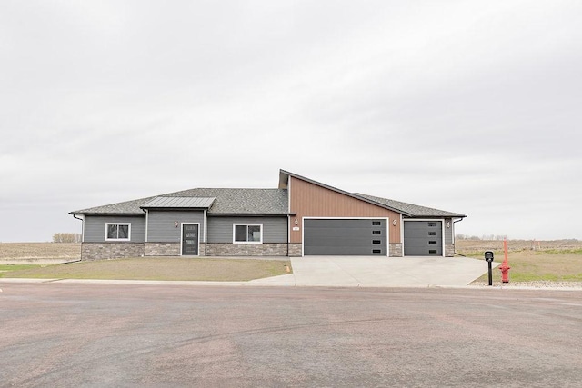 view of front of property featuring a garage, stone siding, and concrete driveway