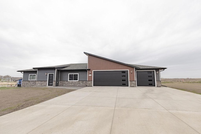 contemporary house with an attached garage, driveway, and stone siding