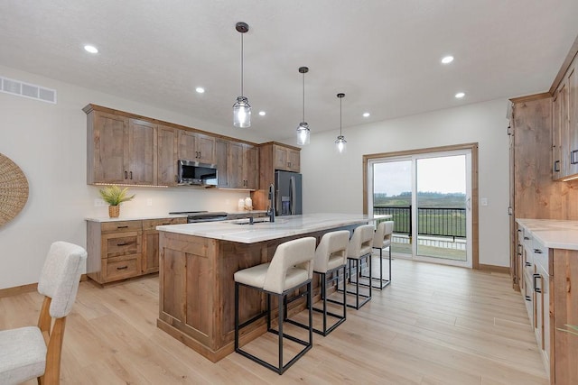 kitchen featuring light wood-style floors, a center island with sink, recessed lighting, and visible vents