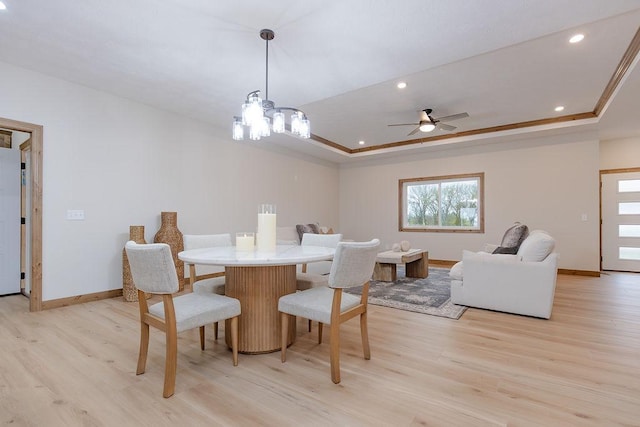 dining area featuring light wood-type flooring, baseboards, ceiling fan with notable chandelier, a tray ceiling, and recessed lighting