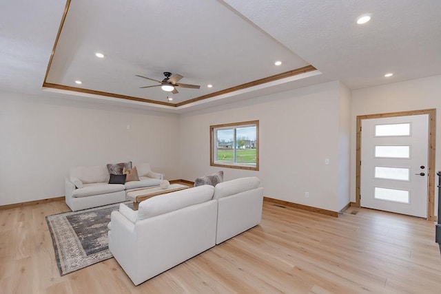 living room with a ceiling fan, a tray ceiling, recessed lighting, and baseboards