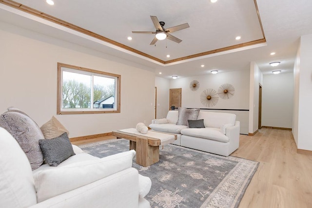 living area featuring a ceiling fan, crown molding, light wood-type flooring, a raised ceiling, and recessed lighting