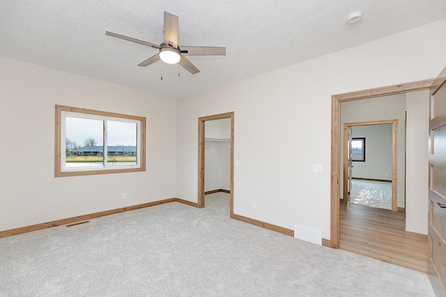 unfurnished bedroom with baseboards, a walk in closet, carpet flooring, and visible vents