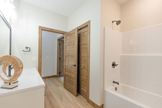 full bathroom with baseboards, bathing tub / shower combination, wood finished floors, and vanity