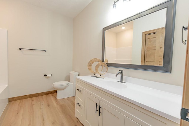 bathroom featuring vanity, toilet, baseboards, wood finished floors, and a shower