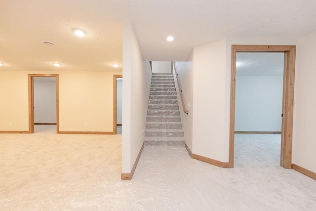 finished below grade area featuring recessed lighting, baseboards, light carpet, and stairs