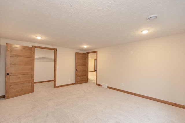 unfurnished bedroom featuring visible vents, baseboards, a walk in closet, and light carpet