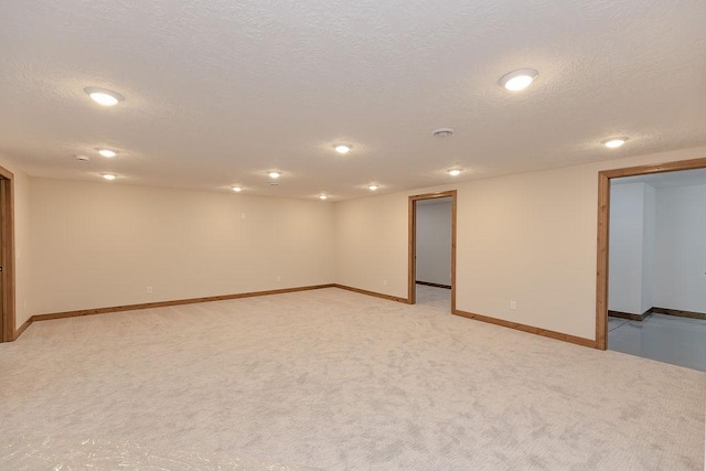 finished below grade area featuring recessed lighting, a textured ceiling, baseboards, and light carpet