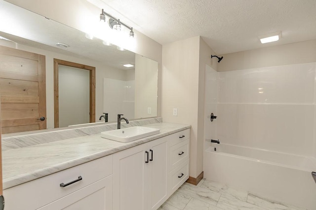 bathroom with a textured ceiling, tub / shower combination, marble finish floor, and vanity