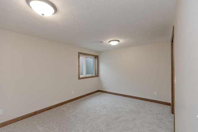 unfurnished room featuring baseboards, light carpet, and a textured ceiling