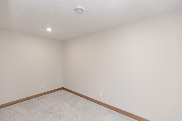 spare room with baseboards, recessed lighting, and light carpet