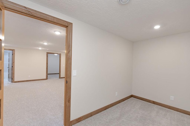 spare room with baseboards, light carpet, recessed lighting, and a textured ceiling