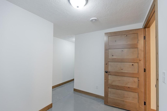 empty room with finished concrete flooring, baseboards, and a textured ceiling