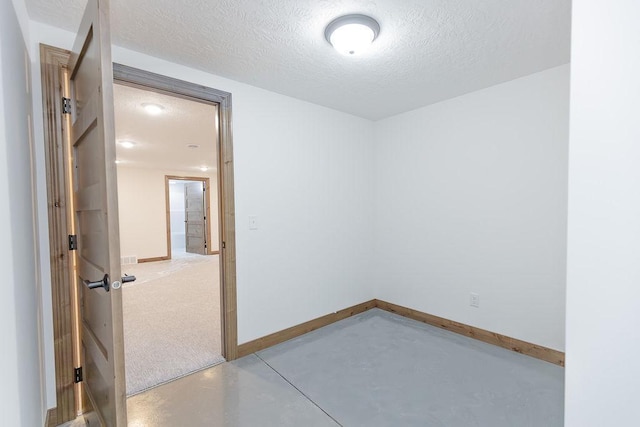 empty room featuring a textured ceiling, concrete floors, and baseboards