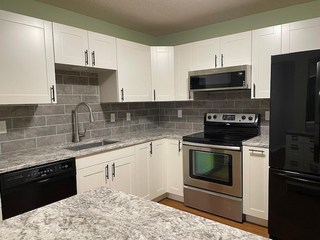 kitchen with black appliances, a sink, white cabinetry, light stone countertops, and a textured ceiling
