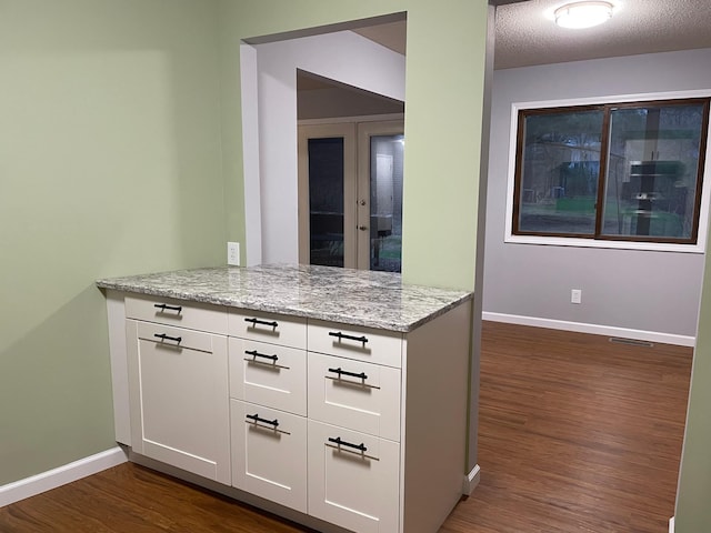 kitchen featuring dark wood-type flooring, baseboards, and white cabinets