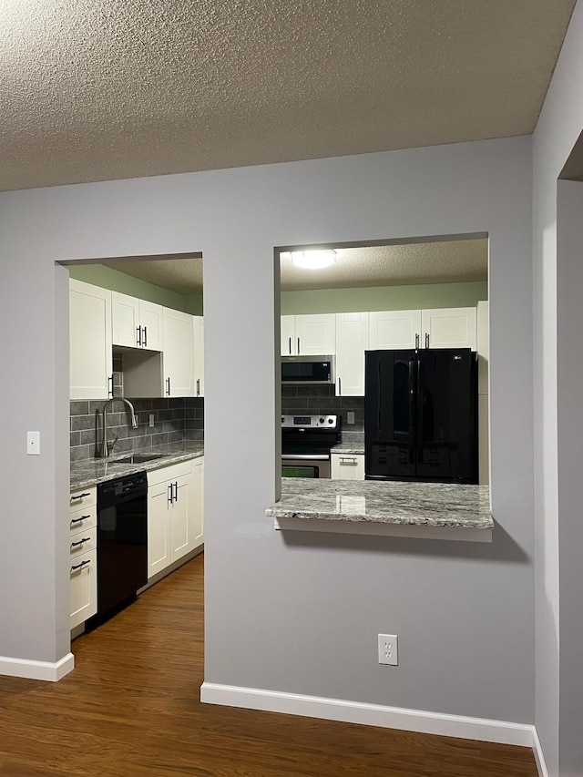 kitchen with black appliances, a sink, decorative backsplash, and dark wood finished floors