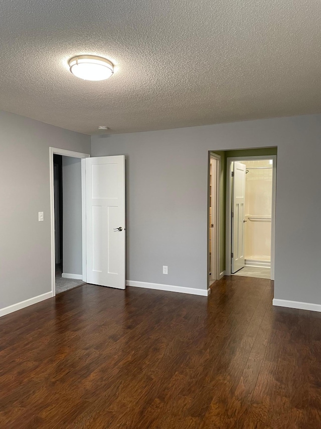 empty room with wood finished floors, a textured ceiling, and baseboards
