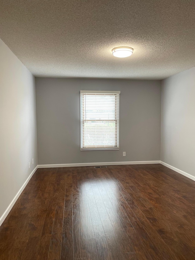 unfurnished room featuring hardwood / wood-style floors, a textured ceiling, and baseboards