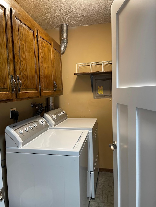 clothes washing area featuring washing machine and dryer, cabinet space, and a textured ceiling