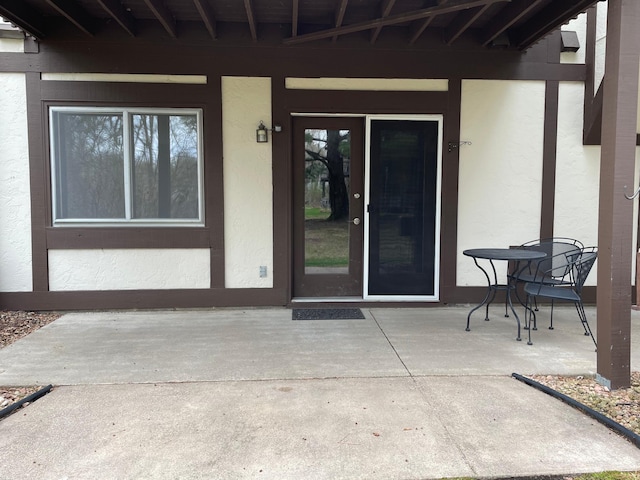view of exterior entry featuring stucco siding and a patio