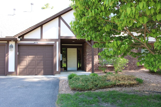 view of front of house with brick siding, a garage, stucco siding, and asphalt driveway