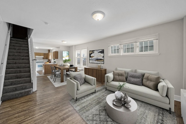 living room with baseboards, wood finished floors, and stairway