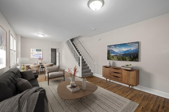living area featuring baseboards, wood finished floors, and stairway