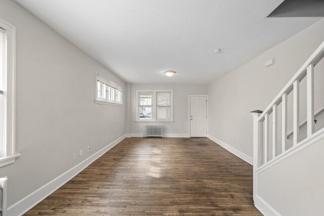 foyer entrance featuring radiator heating unit, baseboards, and wood finished floors