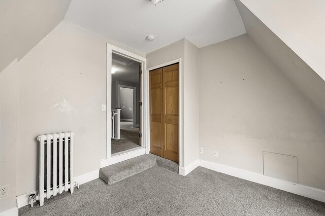 bonus room featuring carpet flooring, baseboards, lofted ceiling, and radiator