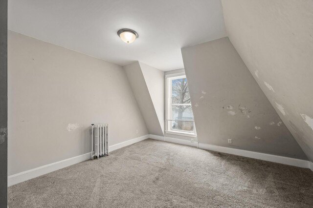 additional living space featuring radiator heating unit, baseboards, vaulted ceiling, and carpet flooring