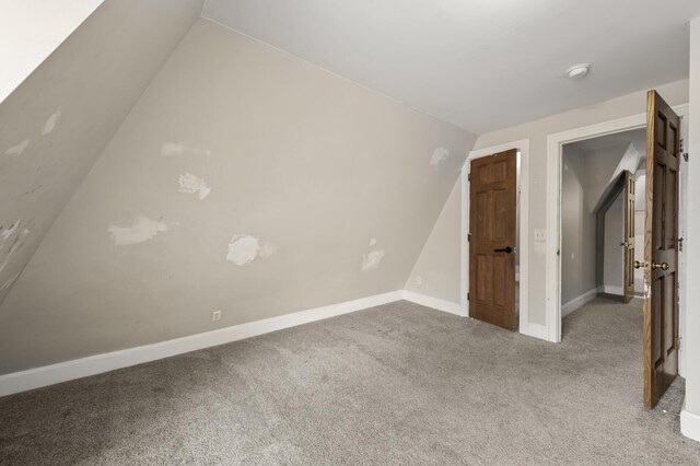 unfurnished bedroom with baseboards, vaulted ceiling, and carpet