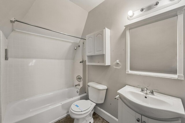 bathroom featuring vanity, toilet, baseboards,  shower combination, and vaulted ceiling