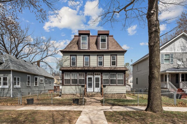 second empire-style home featuring a gate, a fenced front yard, roof with shingles, and entry steps