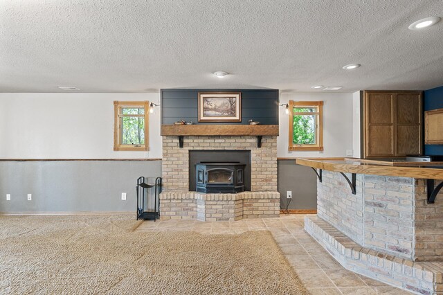 9158 Collins Dr NW, Ramsey, MN 55303 - unfurnished living room featuring healthy amount of natural light, a textured ceiling, recessed lighting, a wood stove, and baseboards