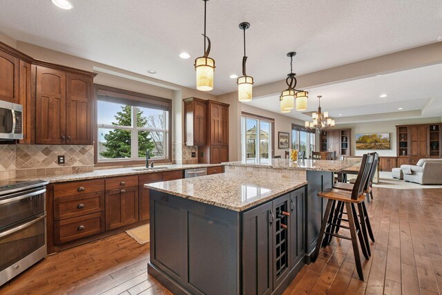 2919 Hilltop Dr, Chaska, MN 55318 - kitchen with appliances with stainless steel finishes, a sink, open floor plan, hardwood / wood-style flooring, and a kitchen island
